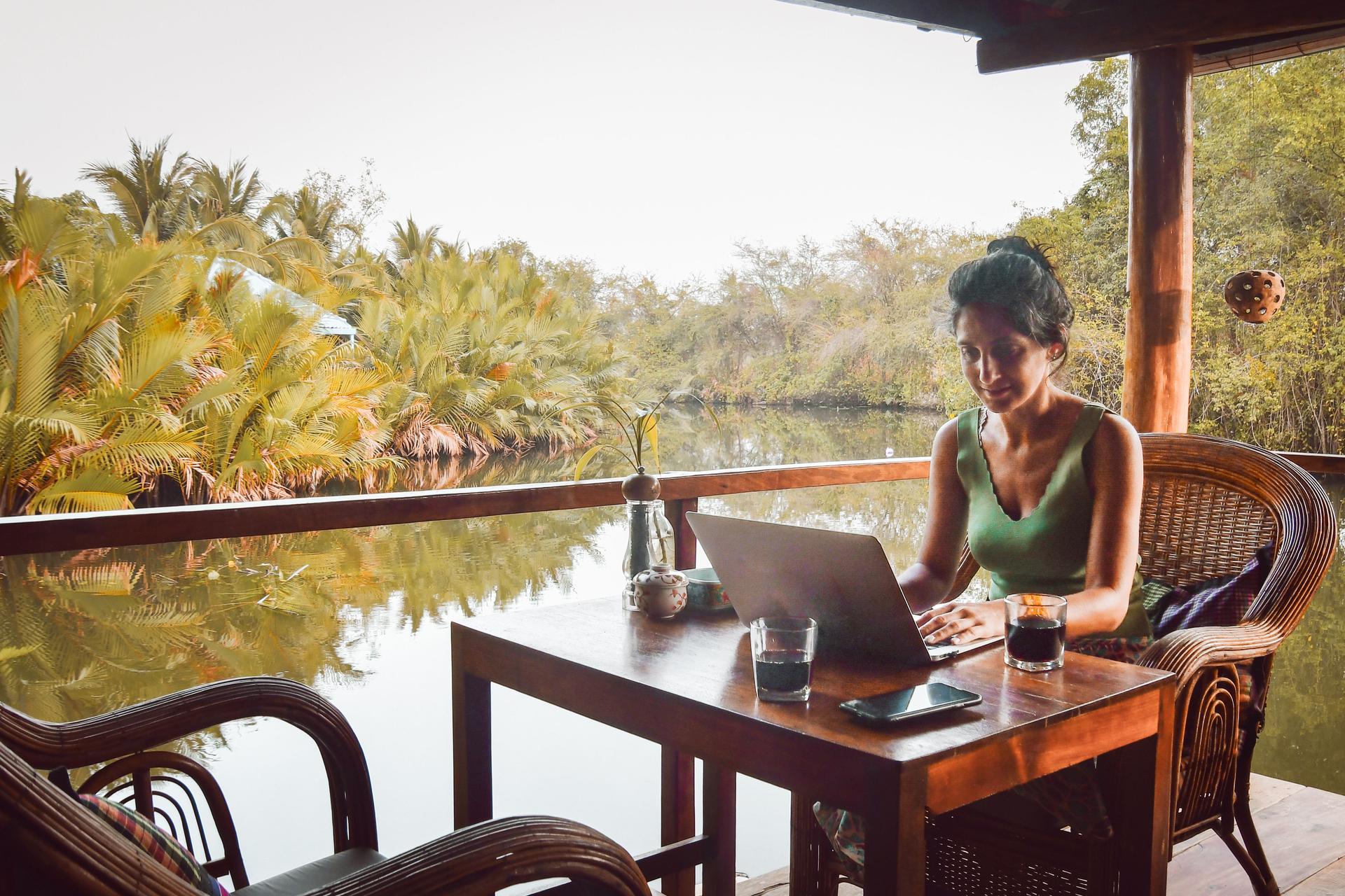 Close up young caucasian woman sit by table in cafe use laptop on holidays in southeast asia in beautiful tropical nature. Remote worker work online abroad concept