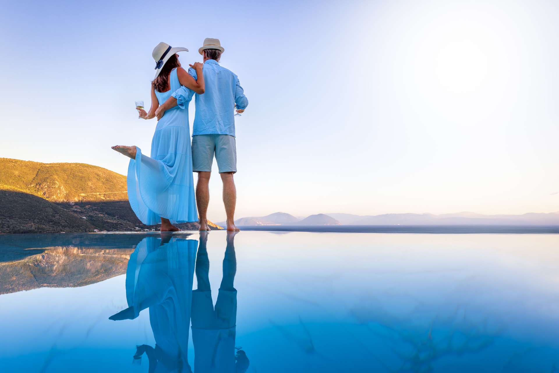 A elegant vacation or honeymoon couple enjoys the mediterranean sunset by the pool
