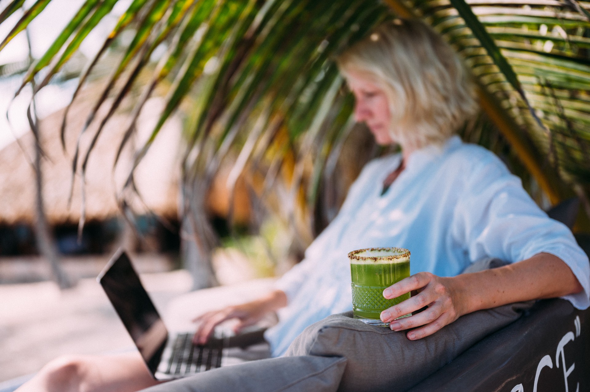 A woman works remotely from a beach restaurant.