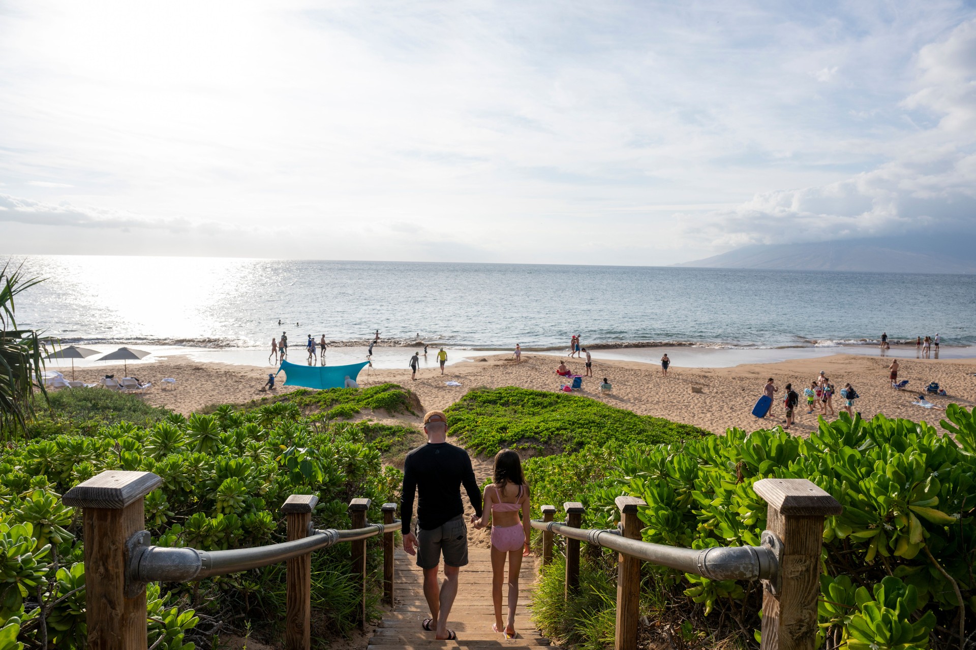 Father and daughters down pathway to beach